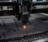 A CNC oscillating knife cutting machine processing a sheet of neoprene for wetsuit production