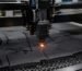 A CNC oscillating knife cutting machine processing a sheet of neoprene for wetsuit production