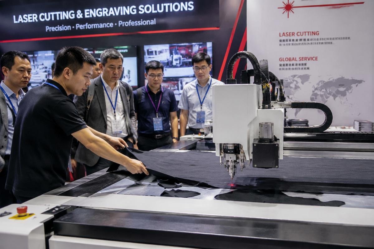 Booth staff demonstrating fabric cutting on CNC oscillating knife machine